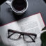 Open book with reading glasses and a cup of coffee