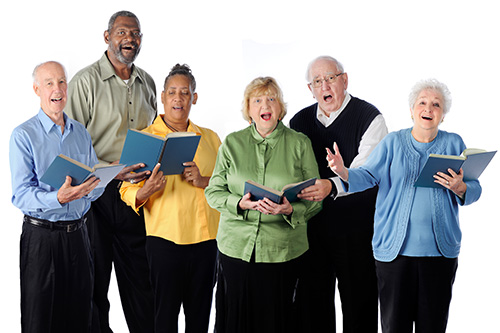 Men and women together singing while holding music in their hands