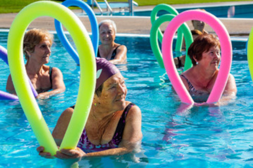 women in a pool holding flexible exercise pool noodles