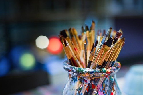 glass jar with various sized paint brushes