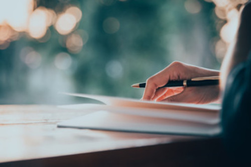 writing Person sitting at a desk writing in a journal
