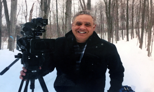 Picture of Mike O'Brian, who is called the Getway Guy, standing outside in the snow holding a camera