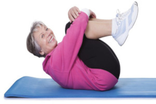 backstrongphoto500 Woman on mat on her back with her arms around her knees.