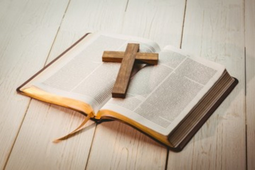 bible wooden cross lying across and open bible