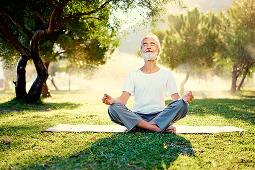 Yoga - meditation and exercise Woman outside on a yoga mat meditating.