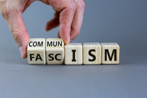 An hand moving dice that spell out fascism, and when turned also spell out communism.