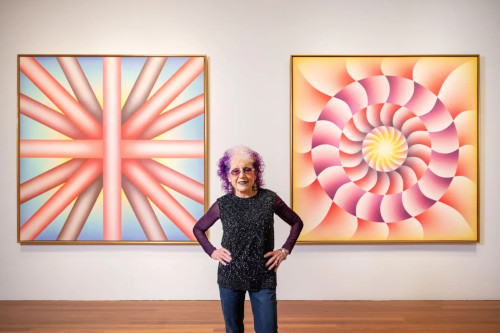photo of Judy Chicago in front of her paintings