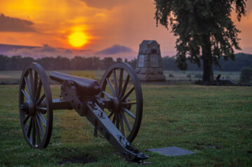 picture of gettysburg at sunset. Cannon and monument in the foreground.