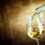 picture of white wine bring poured into wine glasses