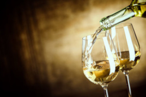 picture of white wine bring poured into wine glasses