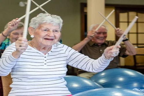 Picture of woman with drumsticks in her hands drumming on an exercise ball