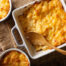 picture of a baking dish with mac and cheese and a wooden spoon ready to serve