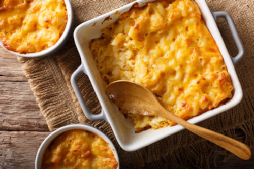 picture of a baking dish with mac and cheese and a wooden spoon ready to serve