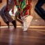 Picture of dancers legs and shoes, on point, but wearing sneakers. Looks like hip hop dancers.