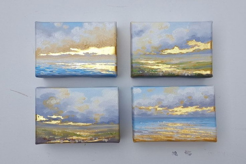 Picture of 4 Triptych paintings of a sky and water with blues and golds.
