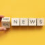 A hand changing blocks that read real news to fake news.