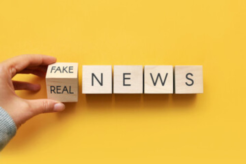 A hand changing blocks that read real news to fake news.