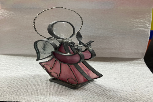 photo of a stained glass angel with a pink dress, white wings and a metal halo