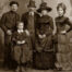 Victorian photo of two men, two women and a young boy. All in hats and fancy dresses and suits.